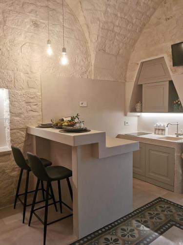 a kitchen with a counter and a bar with two stools at A casòdd' - Luxury Suite in Ceglie Messapica