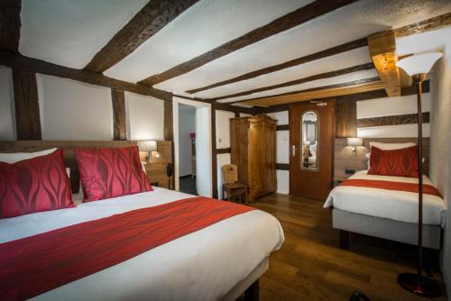 a bedroom with two beds with red pillows at Hôtel De La Couronne in Riquewihr