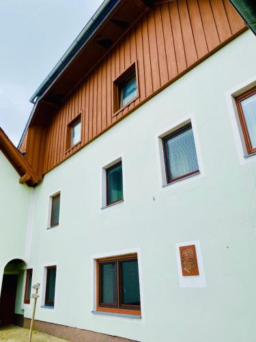 a white building with a wooden roof at Gutshof zum Wurzgarten in Hainbach