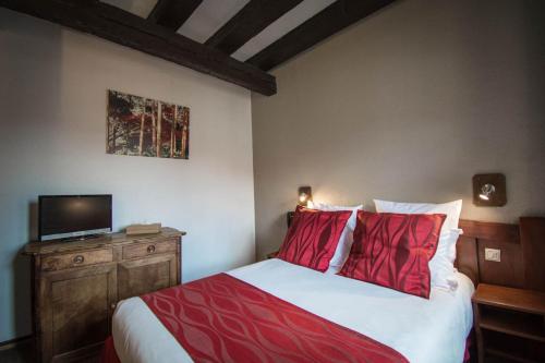 a bedroom with a bed with red pillows and a television at Hôtel De La Couronne in Riquewihr