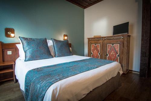a bedroom with a large bed with blue pillows at Hôtel De La Couronne in Riquewihr