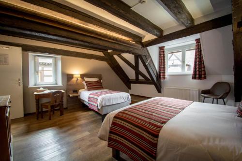 a bedroom with two beds and a table and chairs at Hôtel De La Couronne in Riquewihr