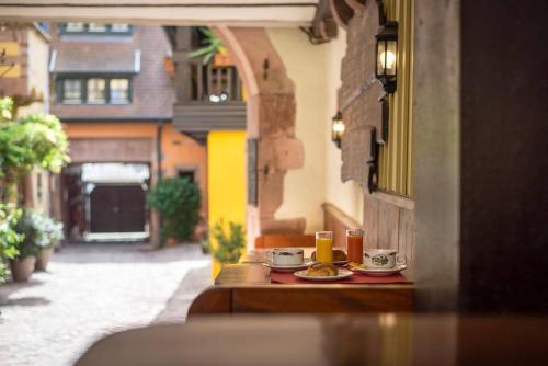 a table with cups and plates of food on a street at Hôtel De La Couronne in Riquewihr