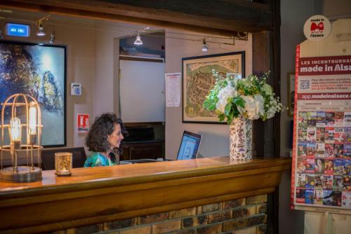 a woman sitting at a counter in a restaurant at Hôtel De La Couronne in Riquewihr