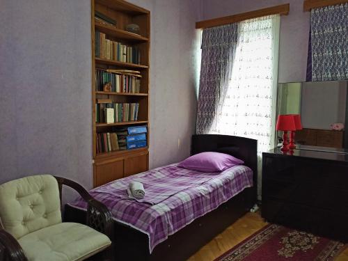 een slaapkamer met een bed, een stoel en een raam bij GuestHouse LILIA &Wine Celler in Telavi