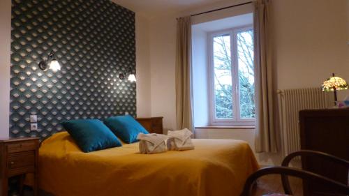 Un dormitorio con una cama amarilla con almohadas azules y una ventana en La ferme du Garnasson- chambre Cassis, en Doranges