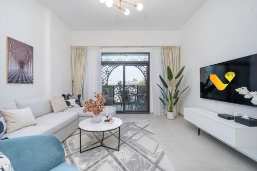 a white living room with a couch and a table at Vogue Vacation Homes, Madinat Jumeirah Living Rahaal Near Burj Al Arab One Bedroom Apartment with Balcony and Vibrant Community View, Access to all Amenities in Dubai