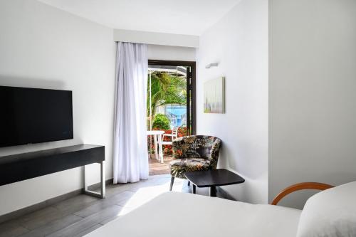 a hotel room with a bed and a tv and a chair at Riviera by Isrotel Collection in Eilat