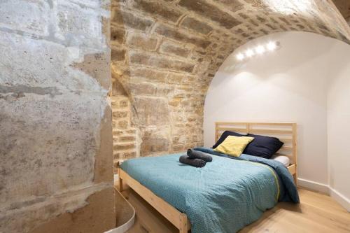 une chambre avec un lit dans un mur de briques dans l'établissement Appartement Broca, à Paris