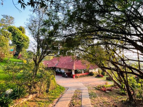 a house with a red roof in a garden at Coorg Daffodil Guesthouse in Madikeri