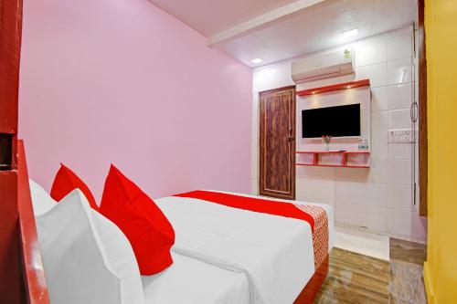 een slaapkamer met een bed met rode kussens en een televisie bij OYO Flagship Hotel Happiness Inn Near Tdi Mall in New Delhi