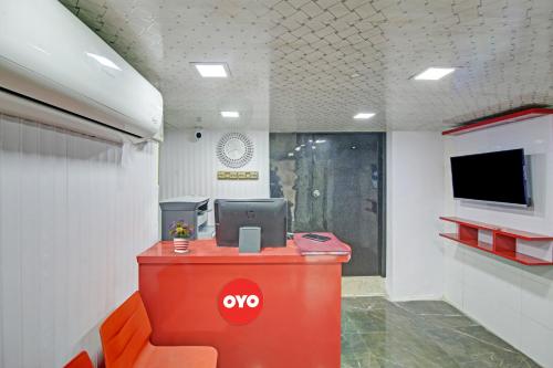een kantoor met een tv en een rode balie bij OYO Flagship Hotel Happiness Inn Near Tdi Mall in New Delhi