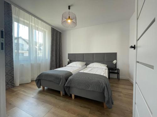 sypialnia z dużym łóżkiem i żyrandolem w obiekcie Avilla Apartamenty w Łebie