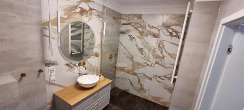 W łazience znajduje się umywalka i lustro. w obiekcie Zamkowa Park Luxury Apartment w Węgorzewie