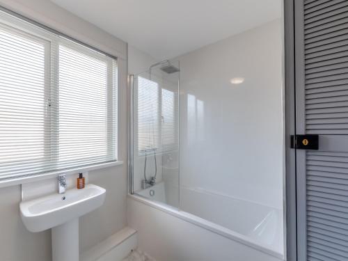 een witte badkamer met een wastafel en een douche bij Hidden Gem in Amble