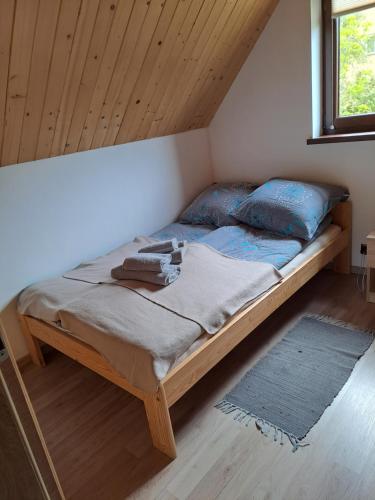 a bed in a room with a wooden ceiling at Dulówka in Smerek