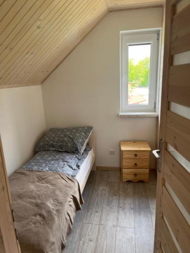 um pequeno quarto com uma cama e uma janela em Noclegi Dąbek em Rymanów