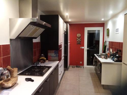 - une cuisine avec une cuisinière et un mur rouge dans l'établissement villa rahuette, à Sète