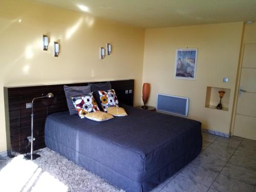 a bedroom with a large blue bed with pillows at villa rahuette in Sète
