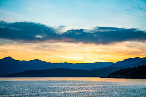 a sunset over a body of water with mountains at SALT COTTAGE Waterfront Guest House with Superb Views in West Vancouver