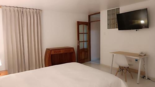 a bedroom with a bed and a desk and a television at Hotel Aural in Cajamarca