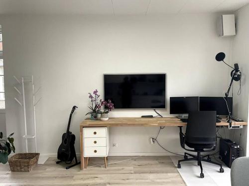 a desk with a computer and a television on it at Eksklusiv villalejlighed m/ have 