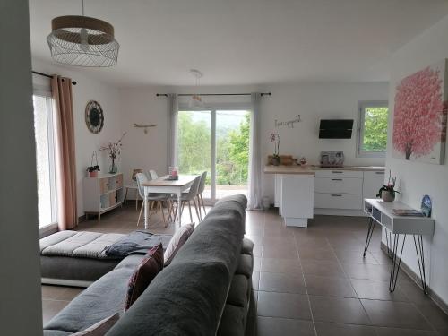 a living room with a couch and a table and a kitchen at Au fond du village in Bassy