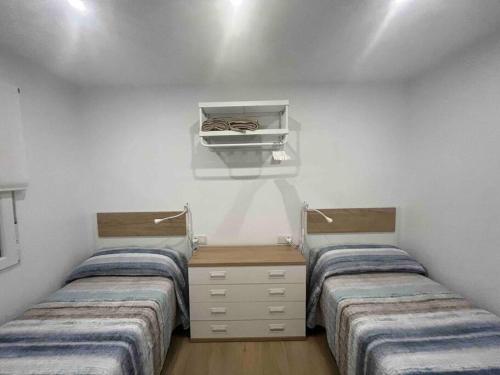 two beds in a room with white walls and wooden floors at Apartamento con preciosas vistas a pie de playa in Santa Pola