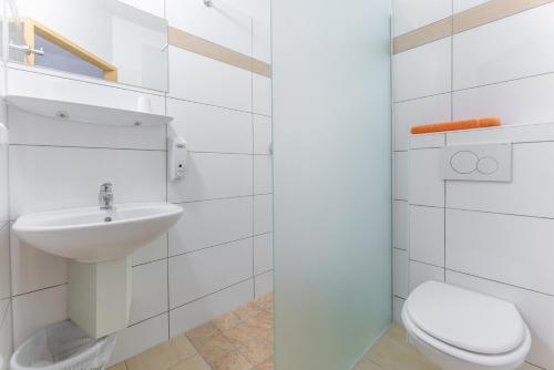 a white bathroom with a toilet and a sink at OEKOTEL Korneuburg in Bisamberg