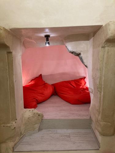 a bed with red pillows in a small room at A Casa di Lu in Minervino di Lecce