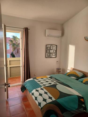 a bedroom with a bed and a sliding glass door at Charmante villa dans village naturiste in Leucate