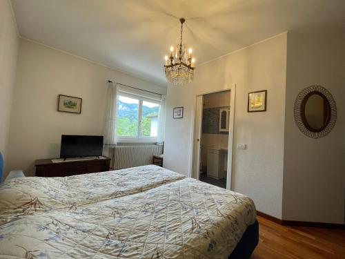 1 dormitorio con cama y lámpara de araña en Appartamento Frieda, en Calceranica al Lago