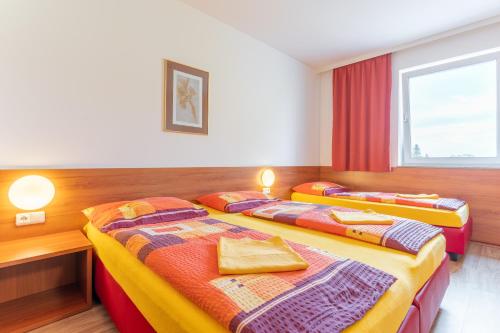 two beds in a room with a window at OEKOTEL Korneuburg in Bisamberg