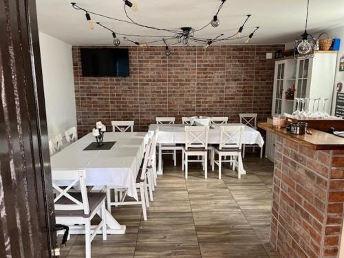 a dining room with white tables and chairs and a brick wall at Ivekova klet, kuća za odmor in Ključić Brdo