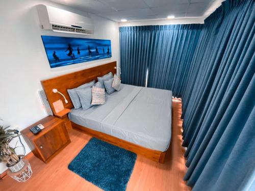 a bedroom with a large bed with blue curtains at Container Villa Collection in Kadawatha
