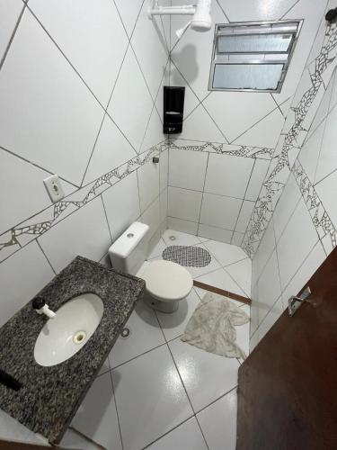 a white bathroom with a toilet and a sink at Apartamento muito aconchegante in Paulista