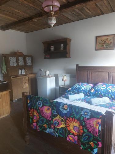 a bedroom with a bed with a flowered blanket and a refrigerator at Agroturystyka LipoweWzgórze- Jaś&Małgosia in Tereszpol