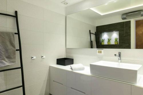 a white bathroom with a sink and a mirror at TLV Luxury Modern Apartment City Center in Tel Aviv