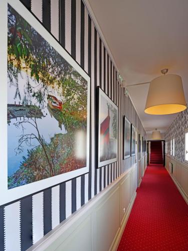 a hallway with paintings on the walls and a red carpet at Hôtel La Résidence des Artistes in Roscoff