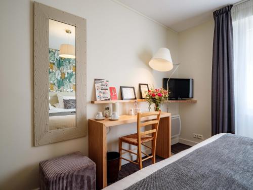 a hotel room with a desk and a mirror at Hôtel La Résidence des Artistes in Roscoff