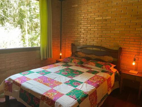 a bed in a bedroom with a brick wall at Aconchego na Serrinha in Resende