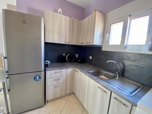 a kitchen with a white refrigerator and a sink at NikLuDin suites & studios in Laganas