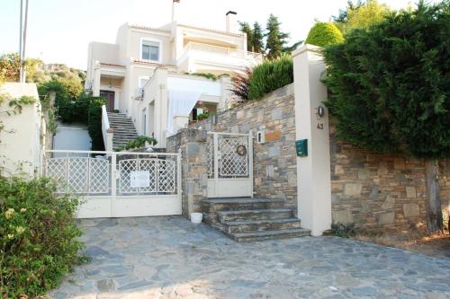a house with a stone wall and a gate at Evelina - Home with View in Volos