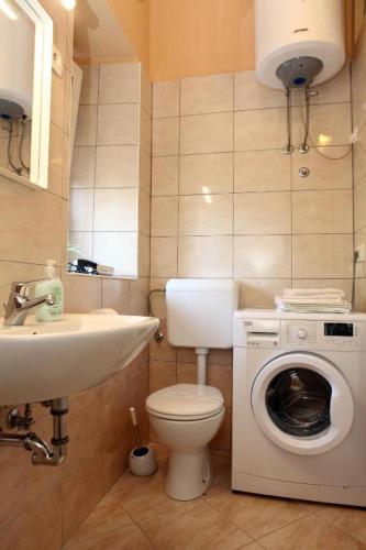 a bathroom with a toilet and a sink and a washing machine at APARTMA JURICICH in Portorož