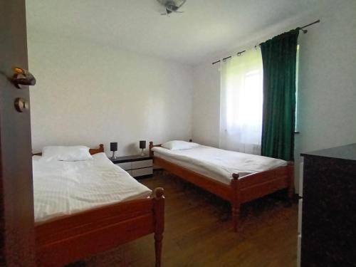 two beds in a small room with a window at Sielski Zakątek in Srokowo