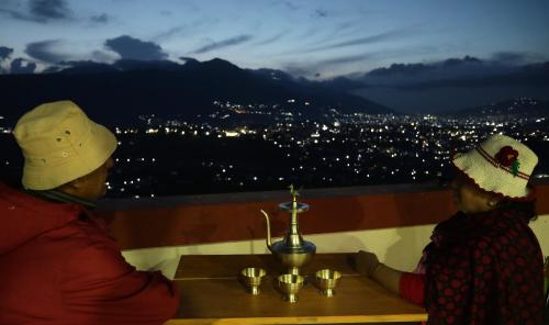 deux personnes assises à une table en regardant une ville la nuit dans l'établissement Kaji Chen, The Tourist Accommodation, à Pātan