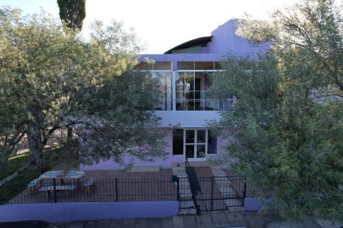 une maison blanche avec des arbres devant elle dans l'établissement Wynwood Extreme Hostel, à Villa Carlos Paz