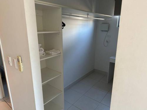 a walk in closet with white shelves and a shower at Lovely 3 Bedroom Condo with Pool in Darwin