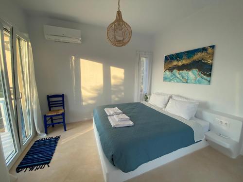 um quarto branco com uma cama e uma cadeira em The Velanidies - Οι Βελανιδιές em Agia Marina