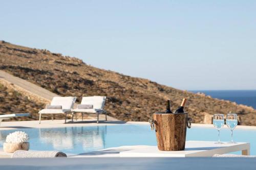 a table with wine glasses next to a swimming pool at Villa Anatoli in Mýkonos City